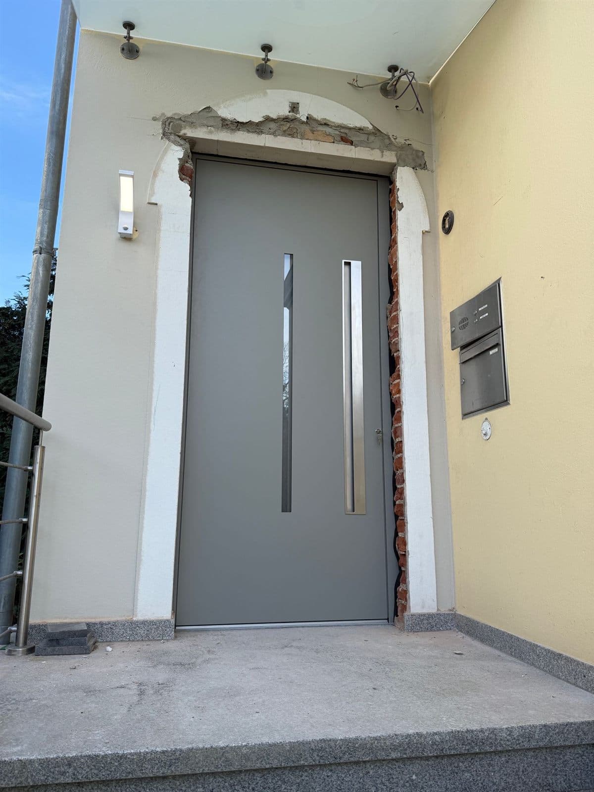 Graue Haustür mit Edelstahlgriff